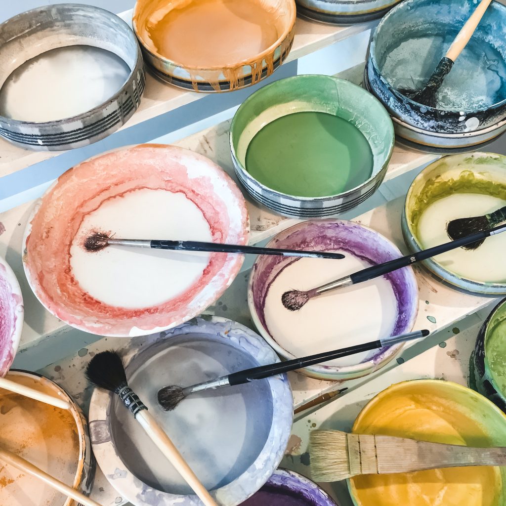 Paint brushes in colorful ceramic plates